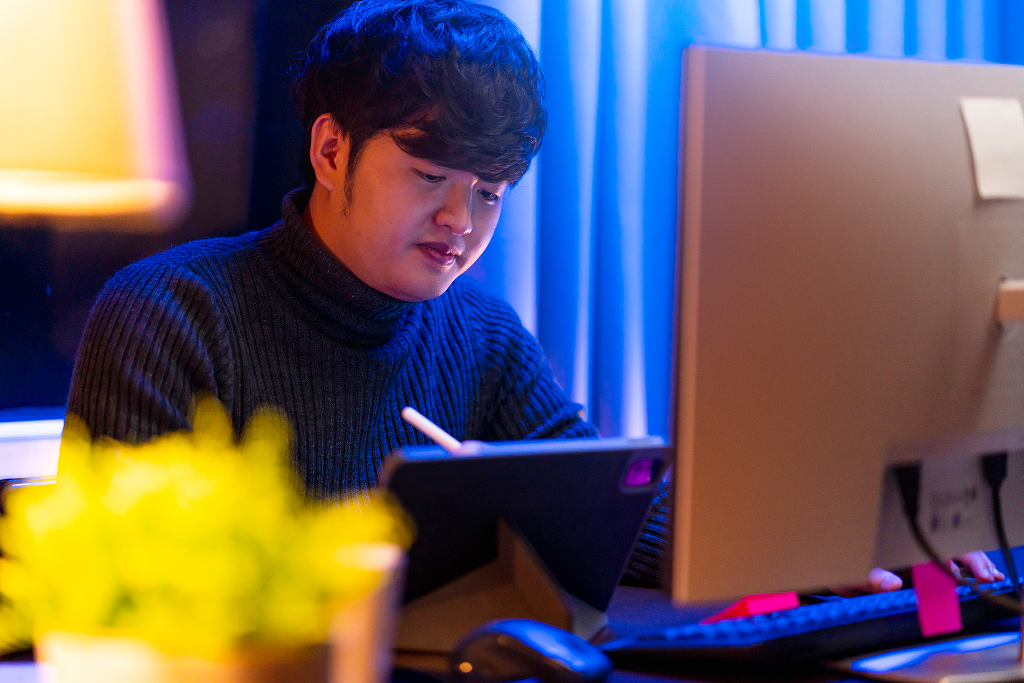 Young Asian freelance creative designer working on a laptop